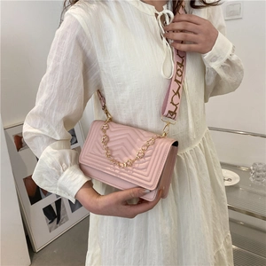 Pink quilted crossbody bag with decorative golden flower chain and wide print strap