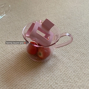 Close-up of a pink square hair claw clip placed on a glass with strawberries