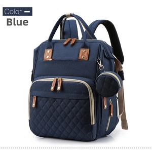 Close-up of blue quilted diaper bag with brown leather accents and a small round pouch