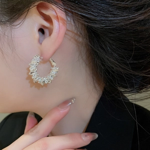 Detail view of silver hoop earrings with alternating rectangular and round cubic zirconia