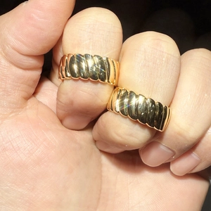 Close-up of golden croissant textured ring with a high-polished finish on hand