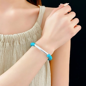 Détail du bracelet ethnique en perles de turquoise avec tube en argent porté au poignet