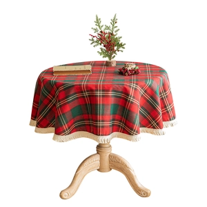 Festive Christmas plaid round tablecloth with gold thread and cream tassels on wooden table