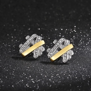 Macro shot of hip-hop stud earrings with interweaving gold and silver lines and cubic zirconia