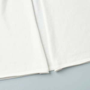 Detail of soft white knit fabric hem and fine stitching on a long-sleeved cardigan