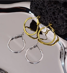 Detail showing polished gold and silver large hoop earrings on a mirror tray and stone