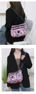 Detail showing multiple zipper pockets and floral nylon fabric on this crossbody bag