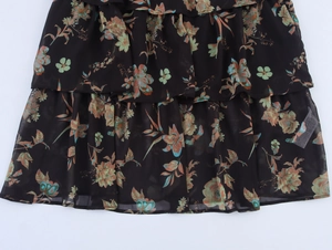 Detail von mehrstufigen Rüschen und Blumendruck auf schwarzem Chiffonkleid