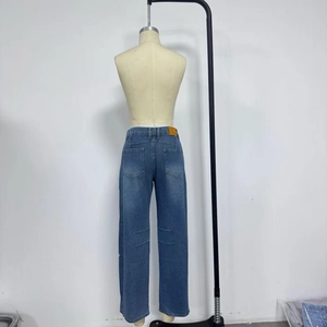 Détail de l'arrière du jean bleu montrant l'écusson en cuir orange et les poches arrière