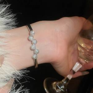 Gros plan d'un bracelet jonc argenté avec sphères en zircone sur le poignet d'un mannequin