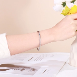 Detail of silver bamboo style stainless steel bangle worn on wrist with floral accents