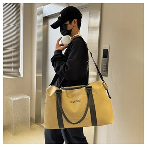 Large yellow gym bag with black straps worn by model in a modern elevator setting