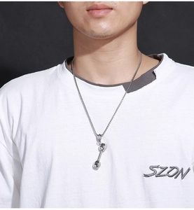 Close-up of a silver dumbbell pendant necklace on a male model for fitness enthusiasts