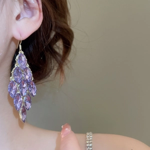 Macro detail of long tassel earrings featuring purple marquise-cut crystals on model