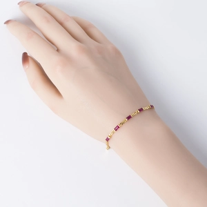 Detailed macro view of a gold-plated bracelet featuring elegant red rectangular gemstones
