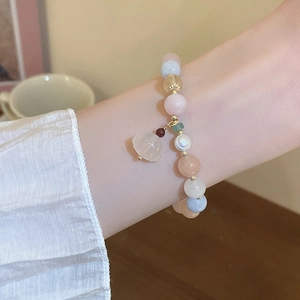 Detail of freshwater pearl and pastel beaded elastic bracelet worn on a female wrist