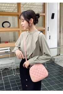 Pink quilted crossbody bag with gold flower clasp shown in a lifestyle street style shot