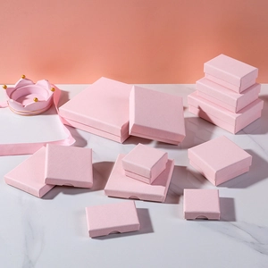 Pink cross-grain paper jewelry boxes for rings and necklaces on marble surface