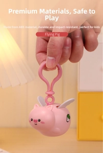 Close-up of pink flying pig keychain toy made of durable ABS material held by hand