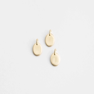 Three minimalist golden oval stainless steel pendants with brushed finish on white surface