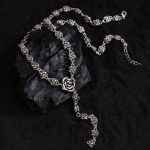 Vintage silver rose necklace with Y-shape pendant design on a dark artistic background