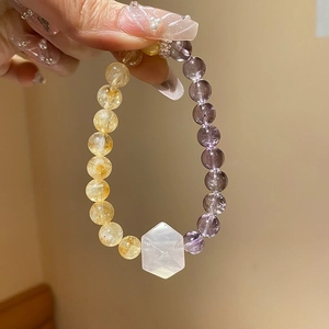 Detail of amethyst and citrine beaded bracelet with hexagonal crystal bead on a hand