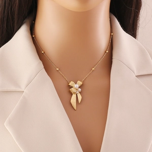 Elegant gold bow necklace with white pearl tassels on a stylish mannequin