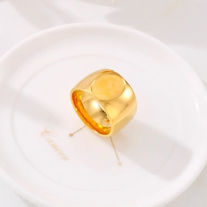 Macro detail of polished gold stainless steel signet ring on a white ceramic plate
