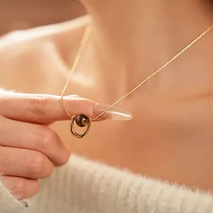 Golden titanium steel tiger eye pendant necklace shown on person with white sweater