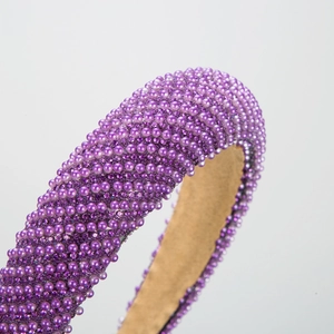 Elegant purple padded headband with faux pearls and crystals on a white background
