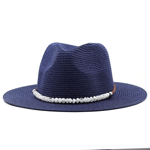 Close-up of navy blue straw sun hat featuring decorative white natural stone beads