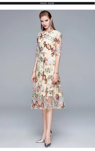 Detailed close-up of intricate floral embroidery on an elegant cream midi dress