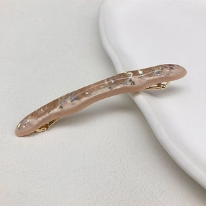 Dettaglio del fermaglio a onde in resina rosa con scaglie dorate e chiusura metallica