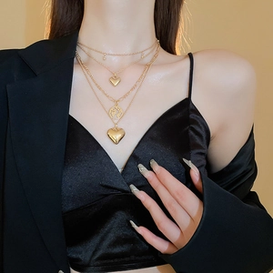 Close-up of a layered gold heart and map pendant necklace on a stylish model