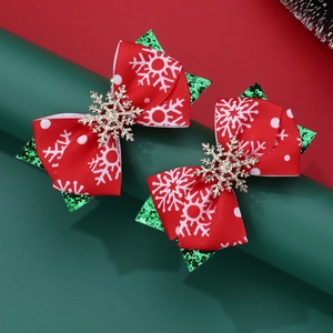 Detail view of handmade Christmas hair clips with red snowflake ribbons and green sequins