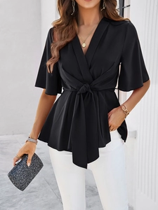 Détail d'une élégante blouse noire à col en V avec nœud à la taille et manches courtes
