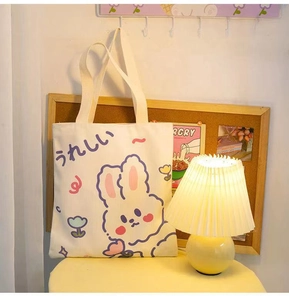 Close-up of cute cream canvas tote bag with cartoon bunny print in a cozy home setting