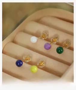 Macro shot of colorful glossy sphere earrings set on beige velvet jewelry display