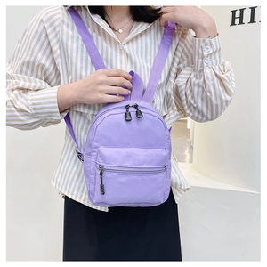 Model wearing purple mini nylon backpack with front pocket and adjustable straps