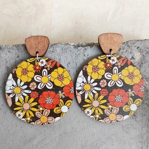 Detailed view of bohemian wooden round earrings with vintage floral patterns on concrete