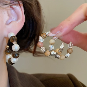 Gros plan détaillé de boucles d'oreilles créoles en C avec perles d'œil de tigre et nacre