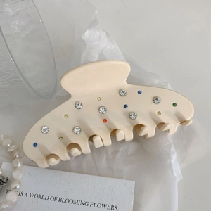 Beige French acetate hair claw clip with colorful rhinestones on white tissue paper