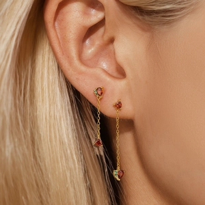 Detail shot of long gold tassel earrings with red heart gems worn by a model