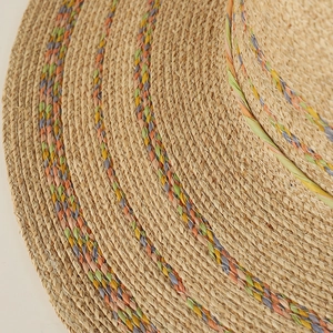 Macro detail of natural raffia sun hat with colorful woven rope trim on the brim