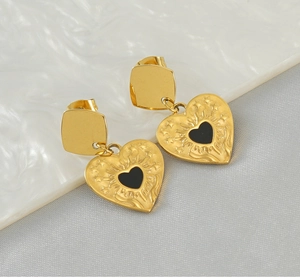 Détail de boucles d'oreilles cœur dorées 18K avec émail noir et gravures soleil