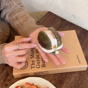 Detailed view of green plush macaron pouch with faux pearl zipper and soft wool texture