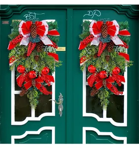 Detail of Christmas swag with red velvet bow, pine cones, and berries on a door