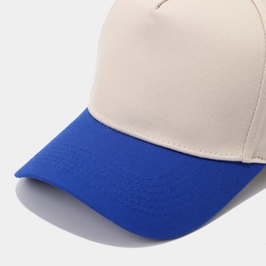 Detail of multi-stitched blue brim and beige twill fabric of the two-tone baseball cap