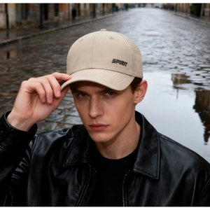 Detail of breathable laser-cut holes and Spirit lettering on a beige baseball cap