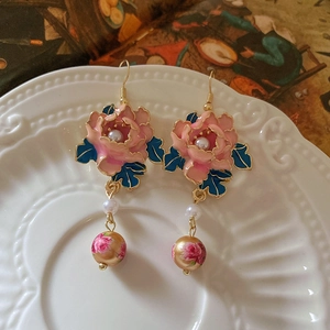 Detail of vintage pink flower oil drop earrings with pearl tassels on retro backdrop